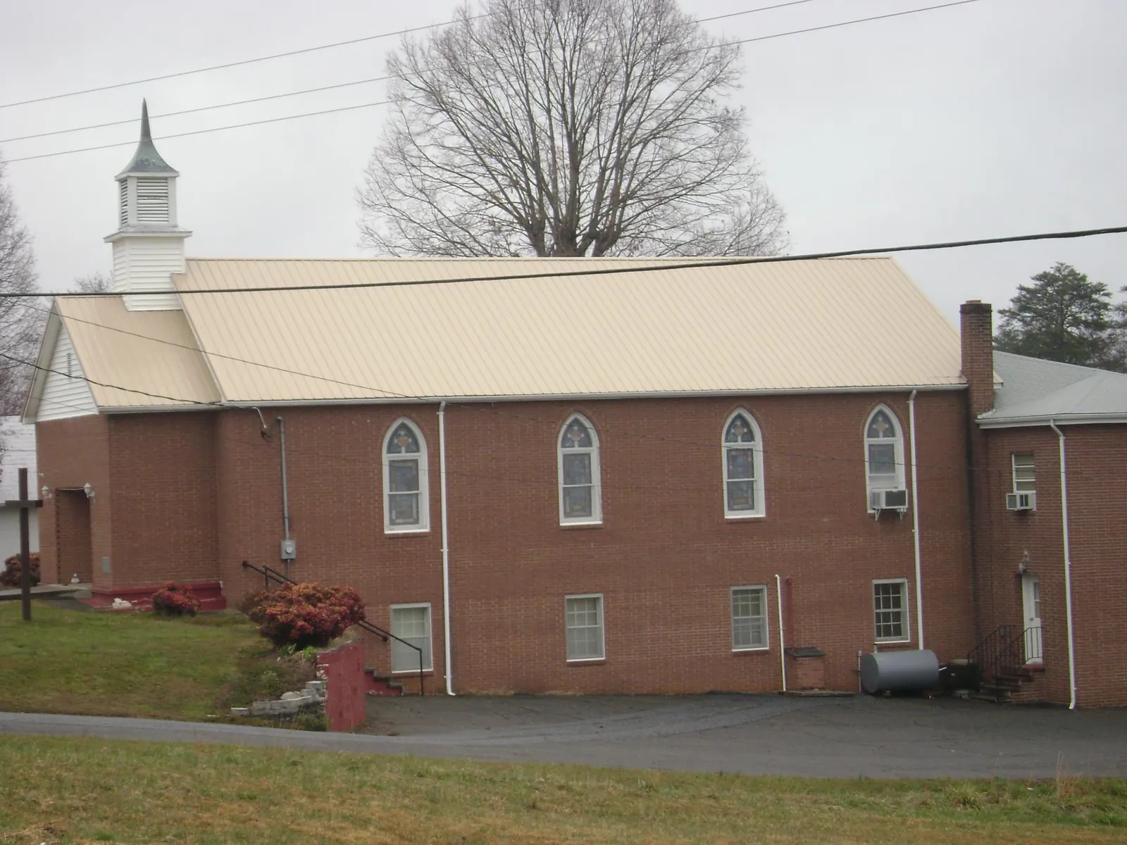 New tan metal roof on a brick church with a white steeple in Cloverdale
