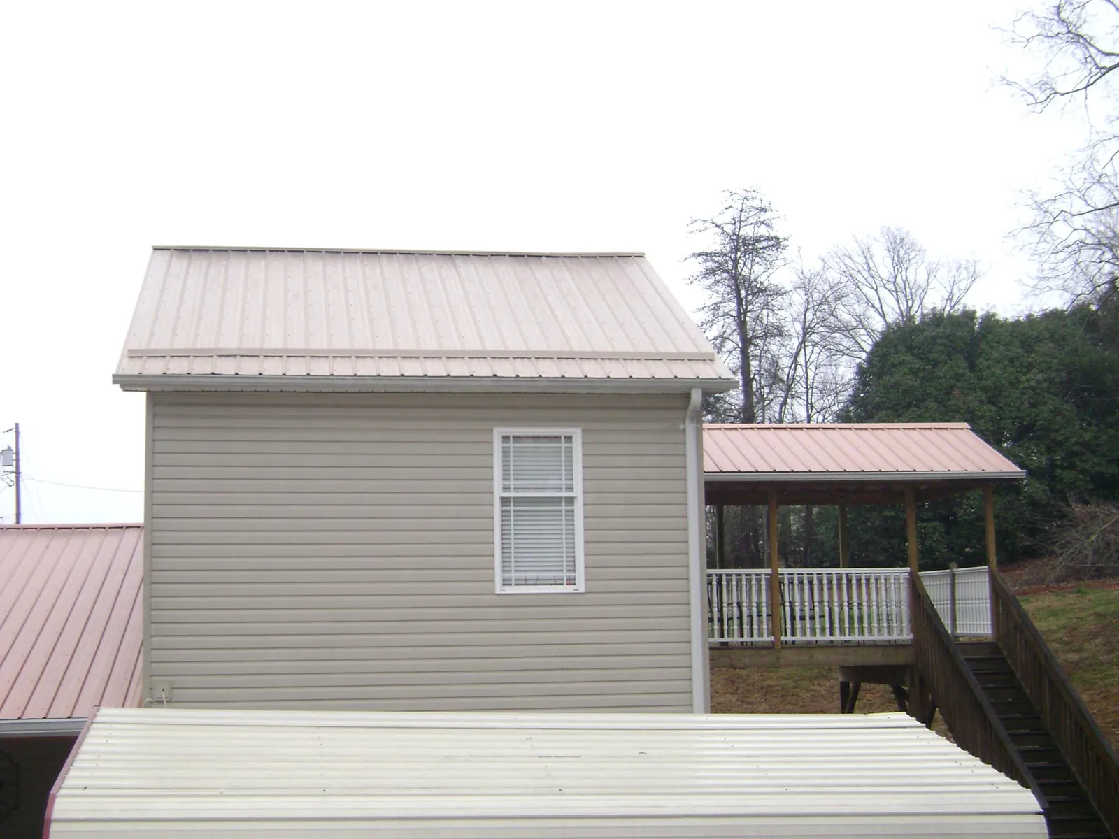 Tan metal roofs on a two story addition and attached porch, from a Roof Replacement job in Cloverdale