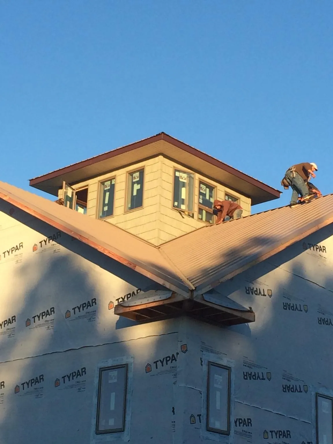 Roofers working around a rooftop cupola on a new metal roof at sunset — Roof Waterproofing in Cloverdale by Roofing Brothers